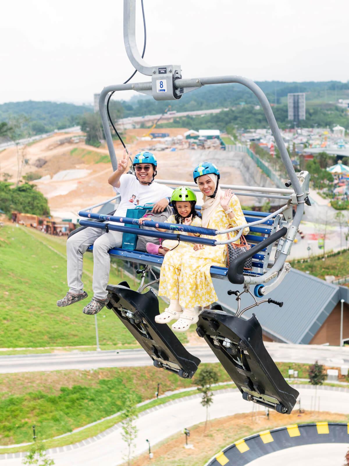 A family of three catches the chairlift to the top of the Luge tracks.