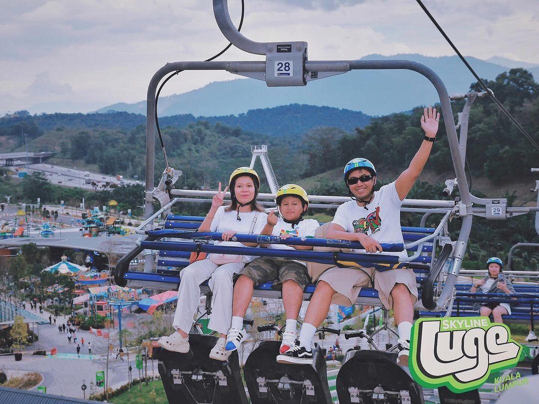 A mother and father ride the Skyride chairlift with their son.