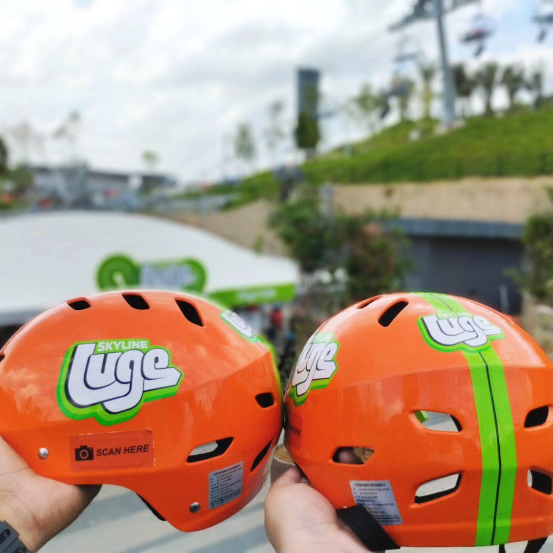 Two Luge helmets held up next to each other.
