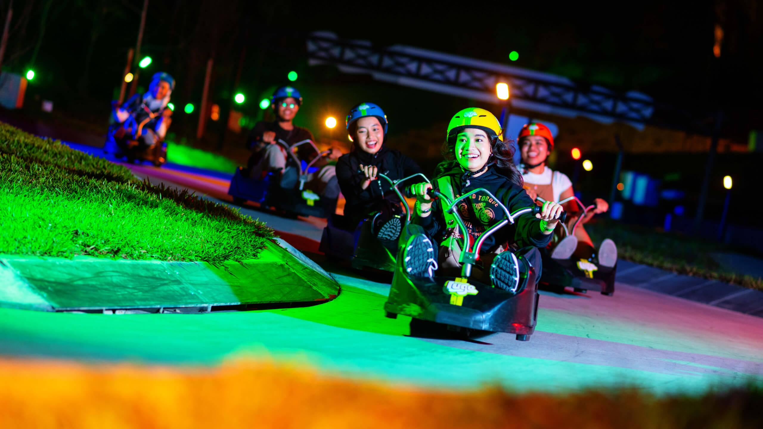 A girl leads her friends down the tracks on the Night Luge.