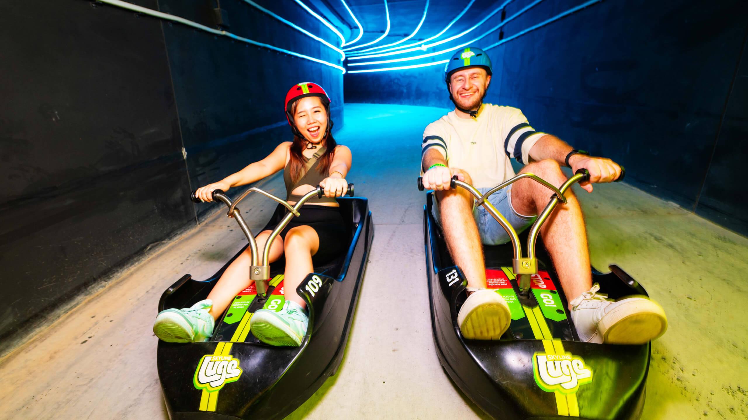 A young couple rides through a tunnel on the Night Luge together.