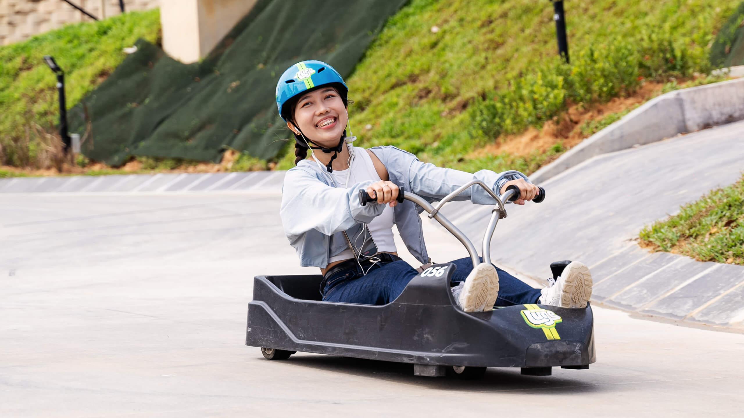 A young lady smiles as she poses for a photo in her Luge cart.