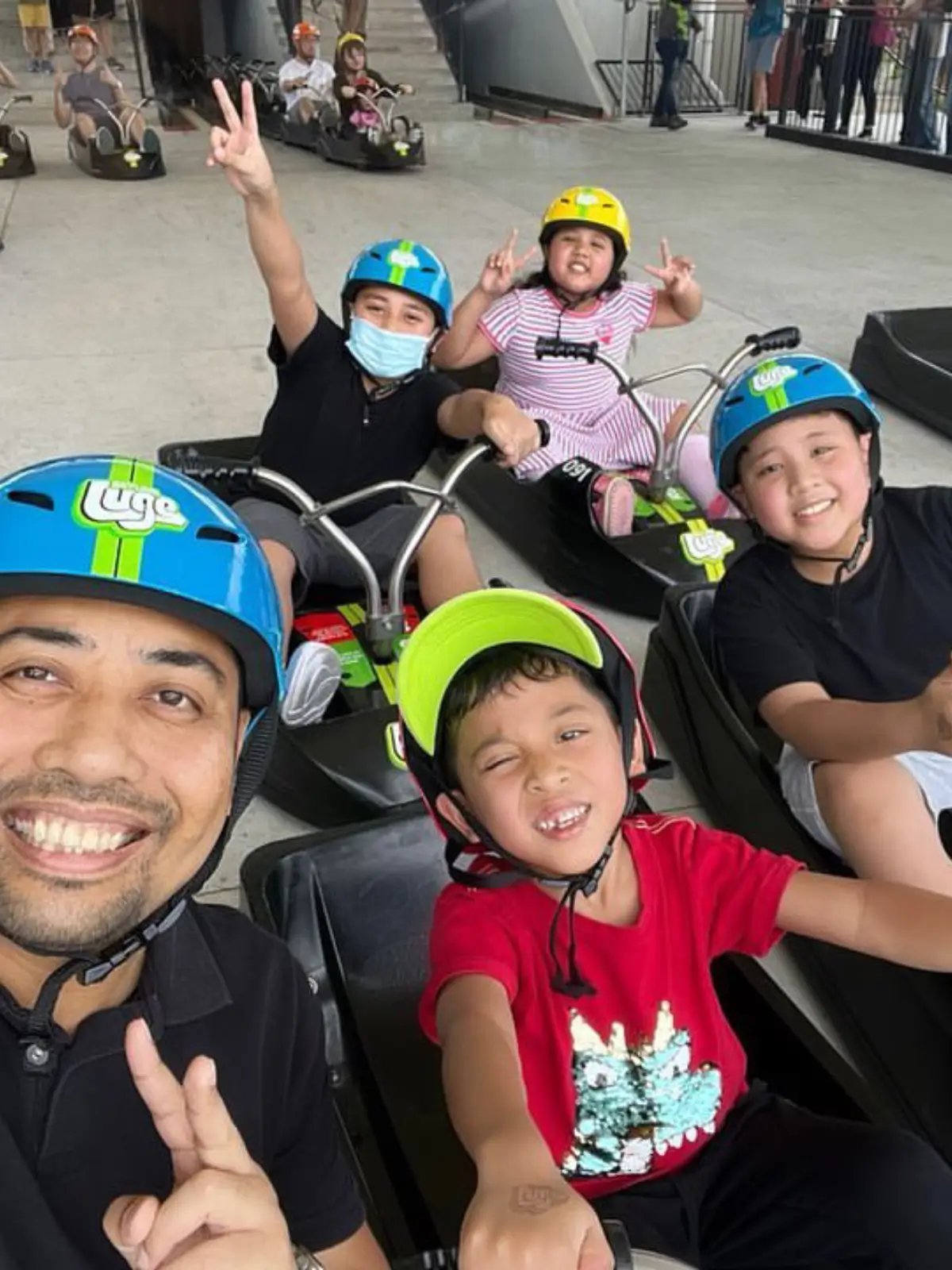 Family and children smiling while riding Skyline Luge carts at the start platform