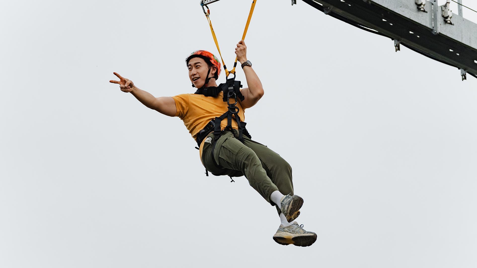 Skyline Luge Kuala Lumpur - a man riding the Hyfly Zipline pointing across with his hand outstretched