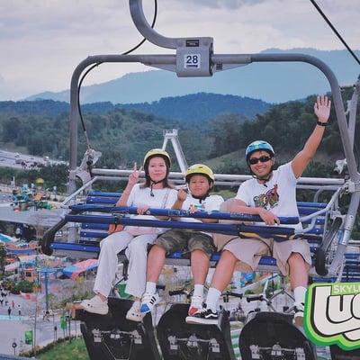 A mother and father ride the Skyride chairlift with their son.