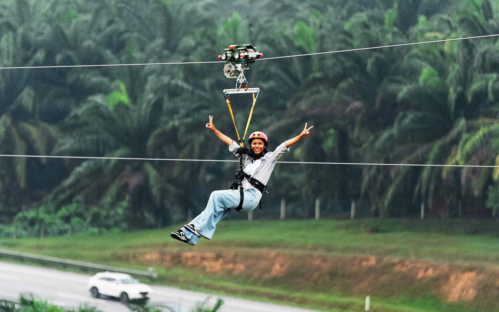 Skyline Luge Kuala Lumpur Hyfly Zipline Rider gliding showing Victory signs