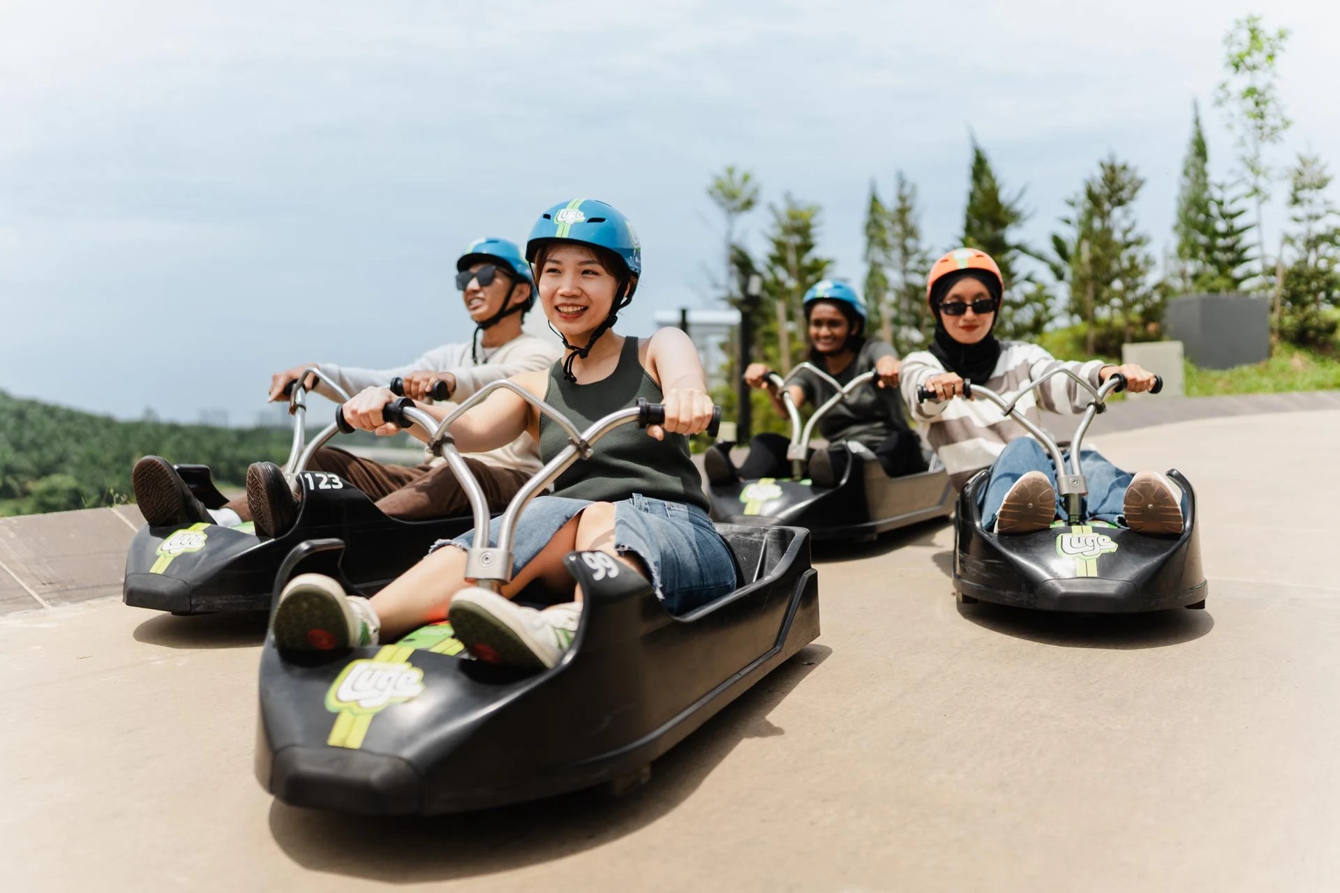 Friends enjoying a Skyline Luge ride, racing downhill in carts on a scenic outdoor track