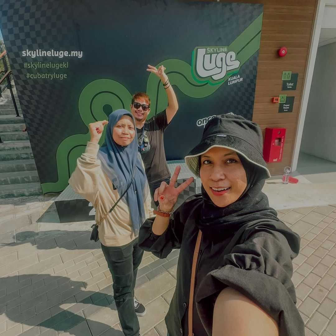A selfie photo with people pulling the peace sign in front of Luge signage.