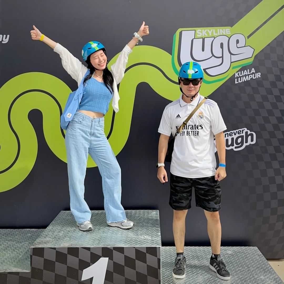 A woman poses on the Luge podium next to her partner.